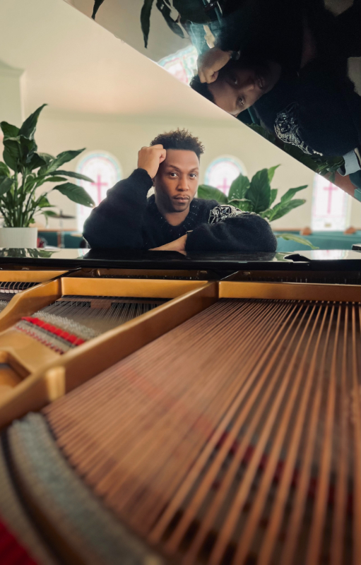 Pop-Soul artist Jason Made seated at a grand piano in a sunlit chapel, looking reflective, used as a press photo for his EPK